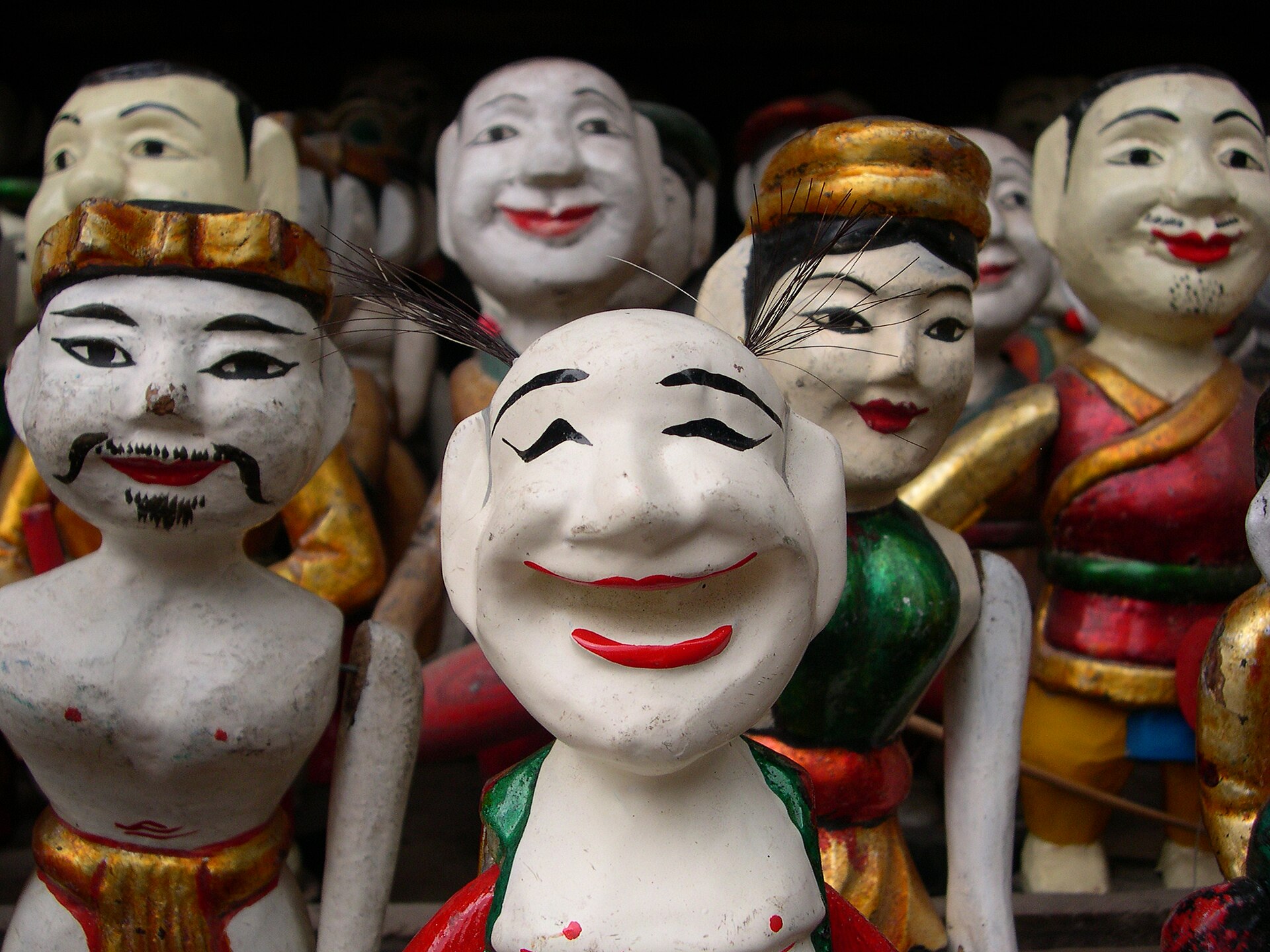 Painted wooden water puppets displayed together in Hanoi’s Old Quarter.