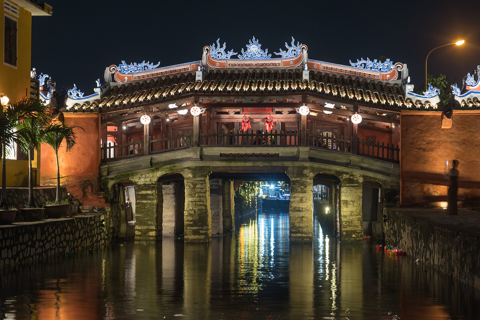 The Japanese Covered Bridge in Hội An illuminated at night and reflected in the water after its 2024 restoration.