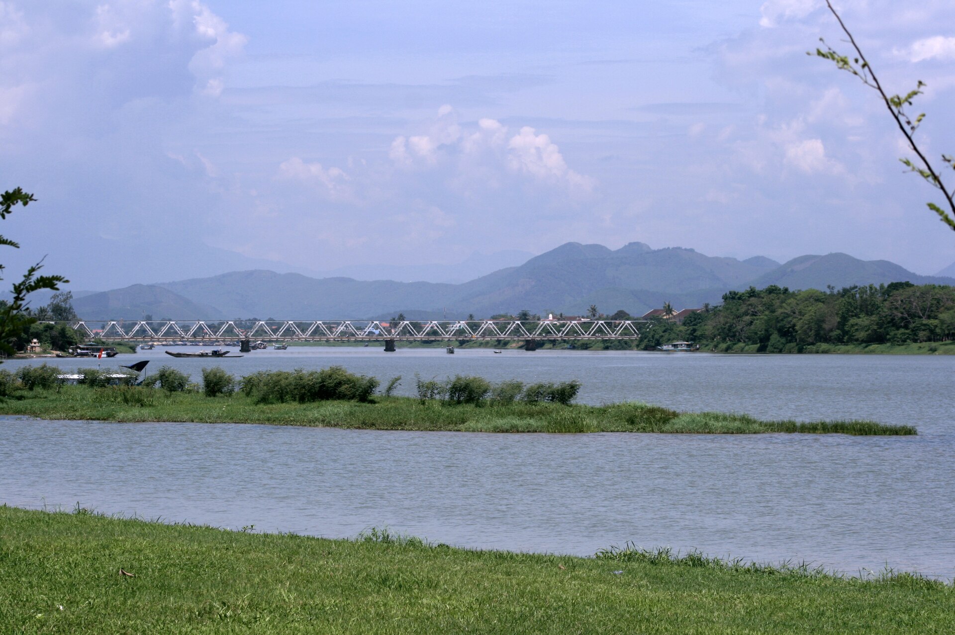 The Perfume River at Huế, with a bridge, green banks and distant hills.