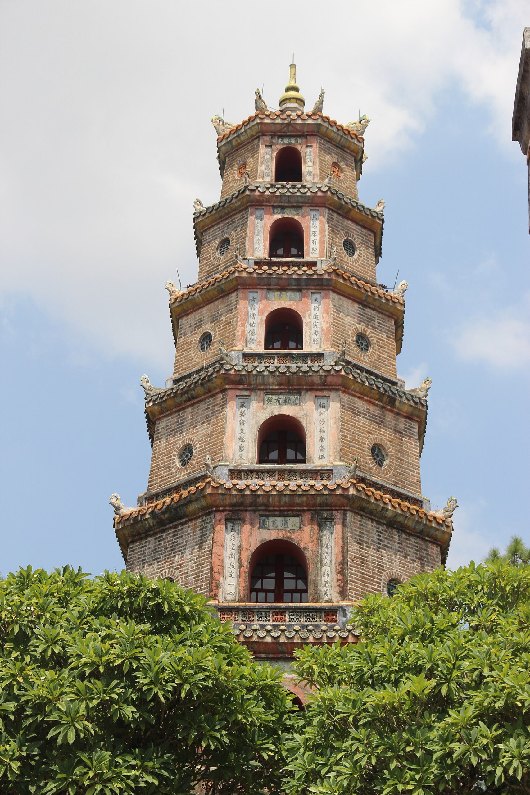 The brick Phước Duyên tower at Thiên Mụ Pagoda rises behind green trees.